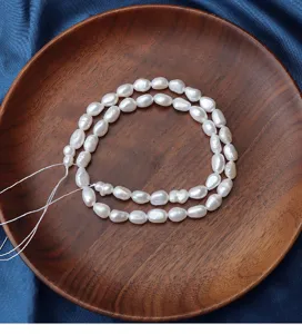 Detailed view of irregular baroque freshwater pearls, 6-7mm white pearls displayed on wooden plate.