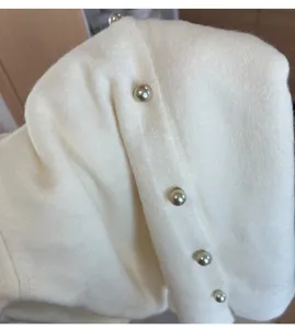 Close-up detail of knitted fabric with elegant pearl buttons, soft texture and fine craftsmanship.
