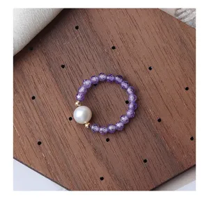 Nahaufnahme Detail des lila amethyst facettierten Perlen Stretchrings auf Holzbrett.