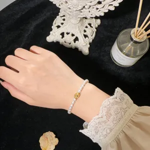 Close-up of elegant freshwater pearl bracelet with gold centerpiece, stylish wrist jewelry detail.