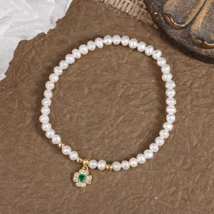 Detailed view of natural freshwater pearl bracelet with green clover pendant and elastic design.
