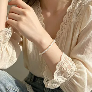 Nahaufnahme eines minimalistischen Barock-Perlenarmbands, elegant am Handgelenk getragen.
