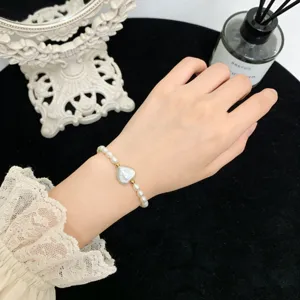 Nahaufnahme des natürlichen Barock-Perlenarmbands mit süßem Herz-Anhänger-Detail.
