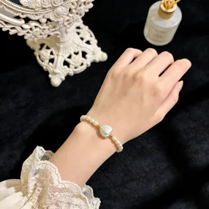 Detailansicht des natürlichen Barockperlenarmbands mit Herzanhänger und goldenen Perlen.