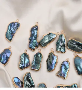 Detail shot of iridescent baroque freshwater pearl charms with gold edges, perfect for DIY jewelry.