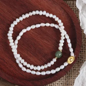 Detailed look at natural freshwater pearl bracelet featuring green jade and gold ingot charm.