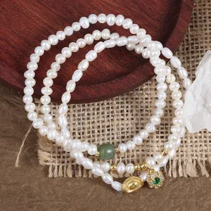Natural freshwater pearl multi-strand bracelet with jade, gold ingot and clover charms detail.