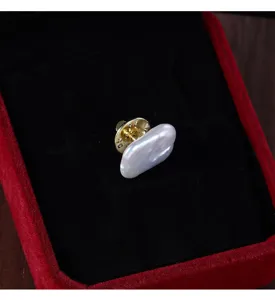 Detailed close-up view of a baroque freshwater pearl brooch pin displayed inside a red velvet box.