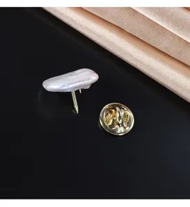 Close-up detail of baroque pearl brooch pin with metallic backing on black background.