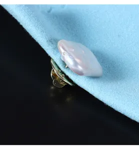 Close-up detail of natural baroque square pearl brooch pin on blue fabric accessory detail shot