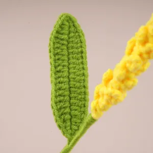 Gros plan détaillé d'une feuille verte au crochet et d'une tige de fleur jaune pour projets DIY.