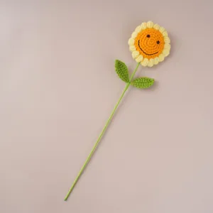 Handmade crochet sunflower flower with smiling face, delicate knitted botanical decor detail.