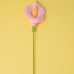 Gros plan de calla rose au crochet fait main avec tige verte, décoration.