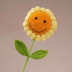Handmade crochet sunflower detail, cute knitted flower with green leaves and a smiley face.