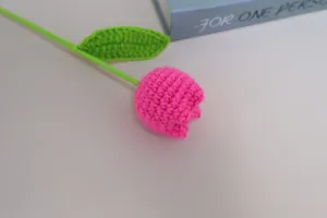 Detailed close-up of handmade crochet wool tulip flower, exquisite knitting texture and vivid color.