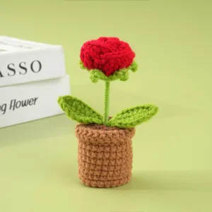 Primer plano de rosa de ganchillo hecha a mano en maceta, linda flor tejida para escritorio.