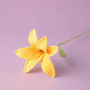 Close up detail of a handcrafted yellow crochet lily flower with green stem and leaf.