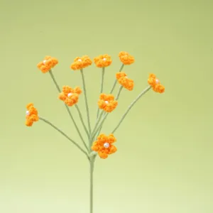 Close-up of handmade crocheted orange flower with pearl center on green stem, lovely detail.