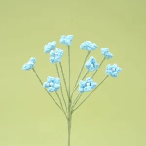 Close-up detail of handmade knitted blue baby's breath flower with pearl center.