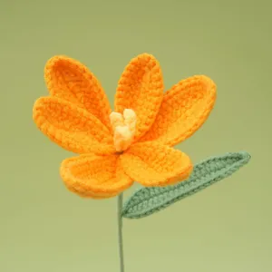 Close-up detail of handmade crochet orange flower with green leaf and stem for decor.