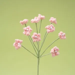 Detailed closeup of handmade pink crochet baby breath flower branch with pearl center for crafts.