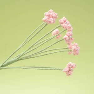 Handmade crochet pink baby breath flower detail closeup with pearl center decoration.
