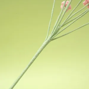 Handmade knitted baby's breath flower stem detail close-up, green wrapped plant decor.