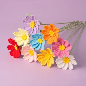 Handmade crochet cosmos flower bouquet detail showing vibrant colorful yarn petals and green stems.
