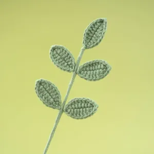 Gedetailleerd overzicht van handgemaakte groene gehaakte plantenbladeren, breigaren detail.
