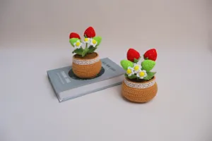 Handmade crochet strawberry potted plant detail view, cute floral desktop decoration display.