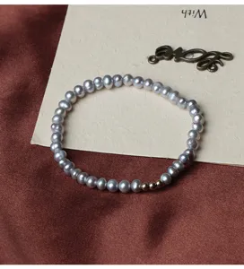 Detail des grauen Süßwasserperlen Armbands mit glänzenden Perlen und goldenen Akzenten.