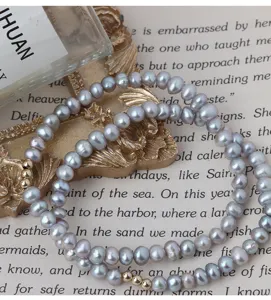 Zarte graue Süßwasserperlen Armband Detail Ansicht mit goldenen Accessoires für elegante Damen.