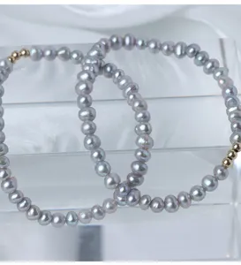 Nahaufnahme des eleganten grauen Süßwasserperlen-Armbands mit vergoldeten Perlen, feines Detail.