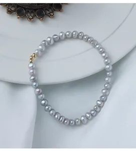 Detailaufnahme des grauen Süßwasserperlen-Armbands mit filigraner Goldperle und sanftem Glanz.