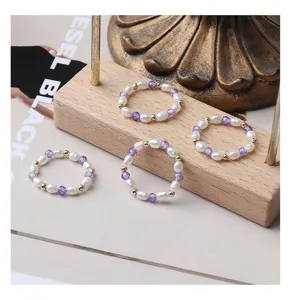 Nahaufnahme von Naturperlen und Amethyst Perlenelastikringen auf Holzdisplay Detail.
