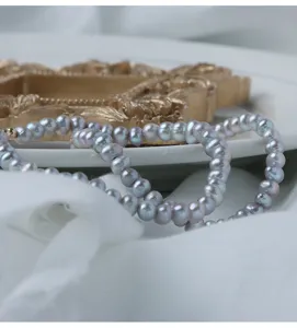 Nahaufnahme eines zarten grauen Süßwasserperlenarmbands mit vergoldeten 14K Elementen.