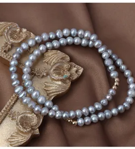 Exquisites graues Süßwasserperlen-Armband Nahaufnahme mit Goldperlen und doppelsträngigem Design.