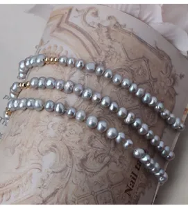 Graues Süßwasserperlen Armband Detailansicht mit goldenen Perlen und elastischem Design.