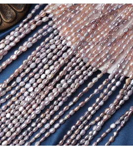Detail van meerdere strengen zoetwaterparels in gemengde snoepkleuren voor knutselen.