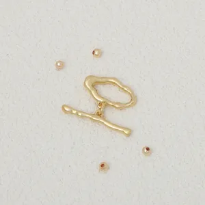 Detalle de componente de joyería DIY chapado en oro con cierre OT y cuentas pequeñas.