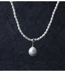 Squisita collana con ciondolo di perle barocche e gancio in argento, dettaglio di gioielleria.