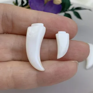Close-up of white mother-of-pearl wolf tooth cabochons for DIY pendant jewelry making.