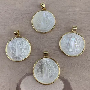 Detail shot of round gold-edged mother-of-pearl pendants with religious engraving for DIY jewelry.