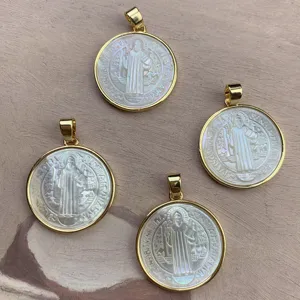 Close-up detail of four gold-rimmed white mother-of-pearl Saint Benedict pendant charms.