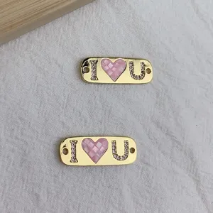 Goldfarbener DIY Schmuckanhänger mit Buchstaben I und U sowie rosafarbenem Herzdetail.