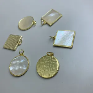 Primer plano de colgantes de joyería DIY de nácar blanco natural con monturas doradas.
