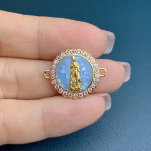Detailed shot of DIY jewelry charm with golden Mary figure, blue shell and pink zirconia.