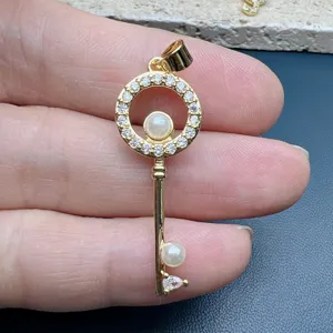 Gold key pendant featuring sparkling cubic zirconia stones and elegant simulated pearls for DIY.