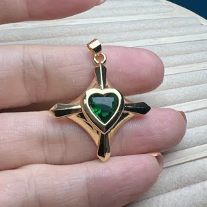 Detailansicht des vergoldeten Kreuz-Anhängers mit dunkelgrünem herzförmigen Zirkonia-Kristall.