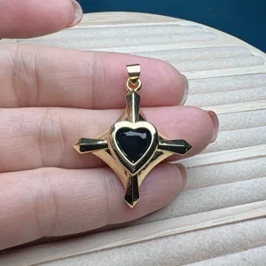 Nahaufnahme eines goldenen Kreuzanhängers mit schwarzem herzförmigen Stein für Halsketten.